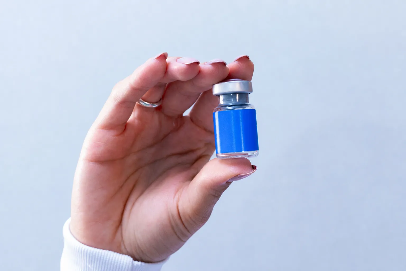 Unlabelled cosmetic filler vial used to explain non-surgical rhinoplasty longevity.